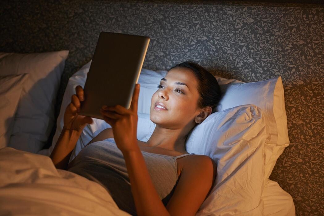 Gece yatakta tablette dizi izleyen kadın